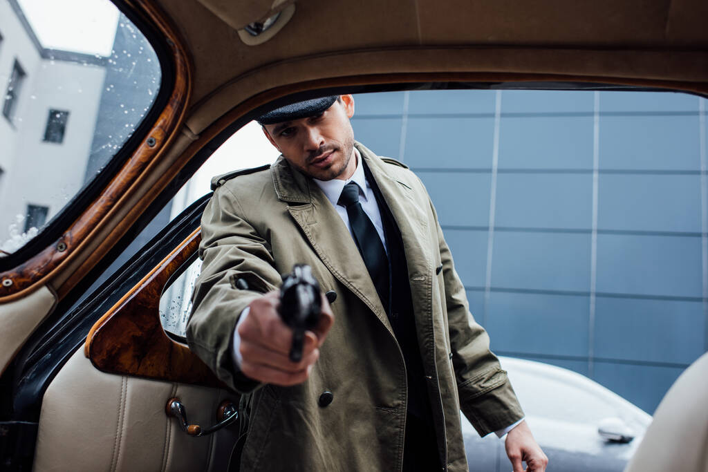 レトロな車に手を伸ばして銃を目指すマフィアの選択的な焦点 - 写真・画像