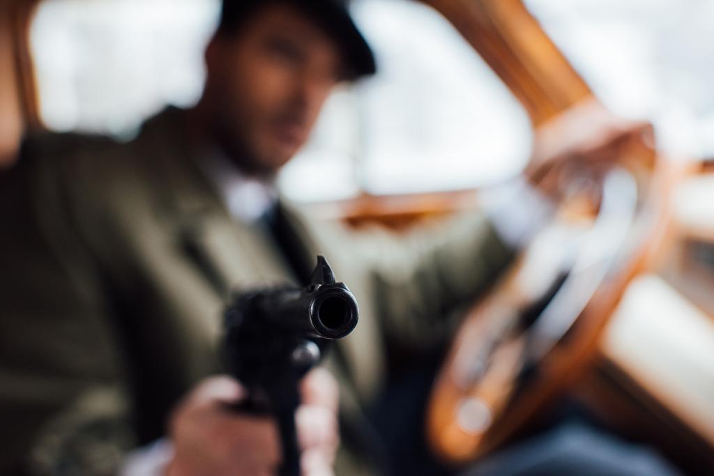 Concentration sélective de mafioso pistolet de visée tout en conduisant une voiture rétro
 - Photo, image