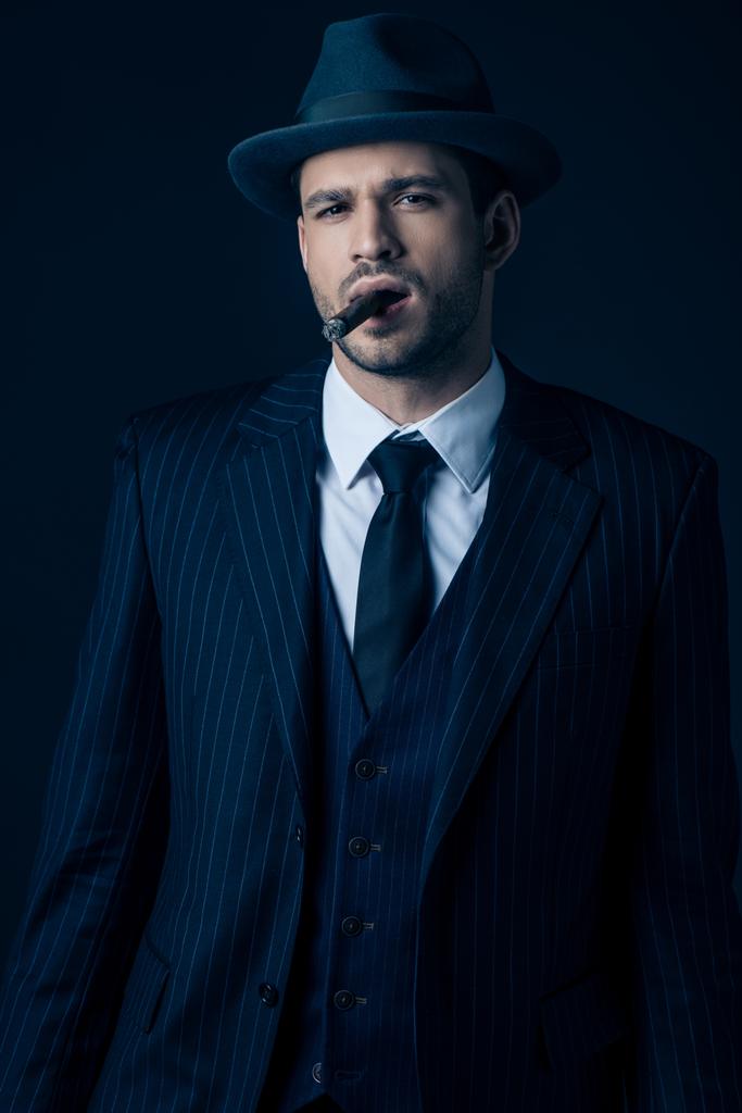 Vista frontal de mafioso fumar charuto em azul escuro
 - Foto, Imagem