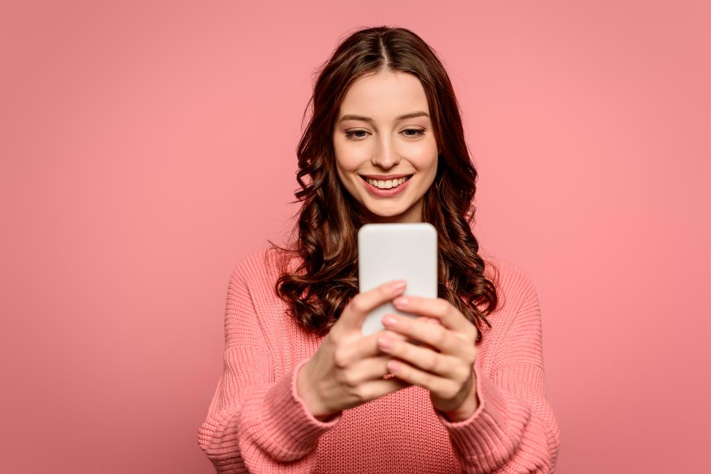 chica feliz sonriendo mientras tiene chat de vídeo en el teléfono inteligente aislado en rosa
 - Foto, Imagen