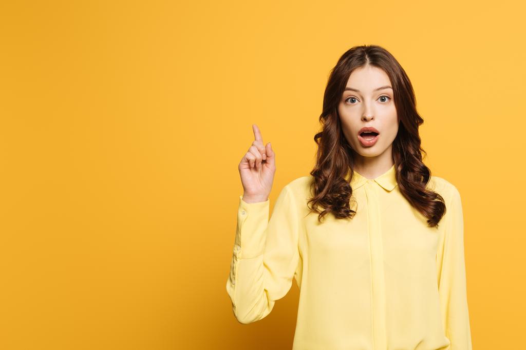 surprised girl showing idea gesture while looking at camera on yellow background - Photo, Image