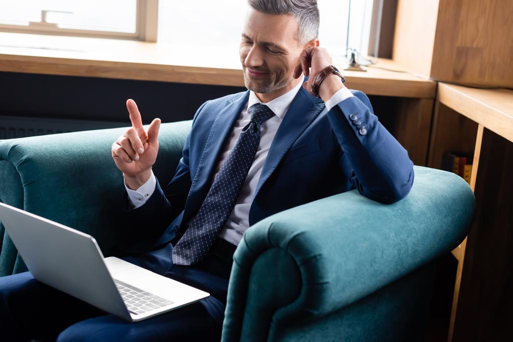 uomo d'affari sorridente in giacca e cravatta utilizzando il computer portatile e mostrando segno idea
  - Foto, immagini
