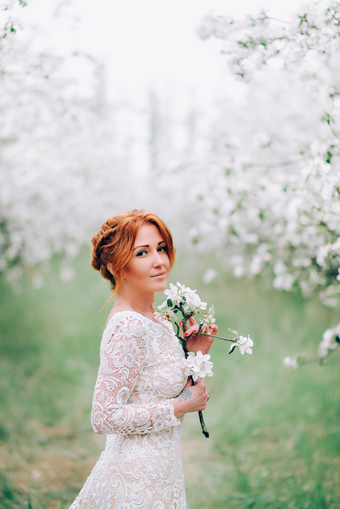 Portrait of a red-haired woman in white blossom. - 写真・画像