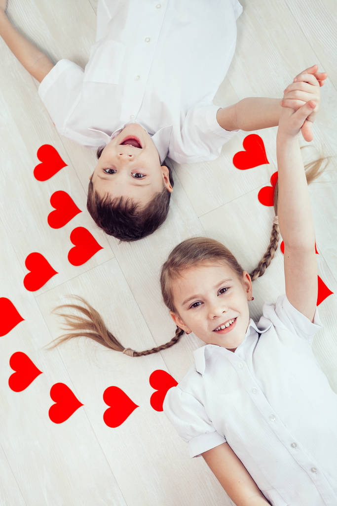 Kleine jongen en meisje liggen op de grond. Concept van een gelukkige Valentijnsdag en broer en zus voor altijd samen - Foto, afbeelding