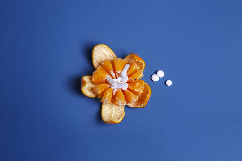 Gyógyszer koncepció friss tisztított mandarin és tabletta közepén citrus. Genetikailag módosított gyümölcs klasszikus kék háttér Másolás hely, felső nézet. Lapos fektetés - Fotó, kép