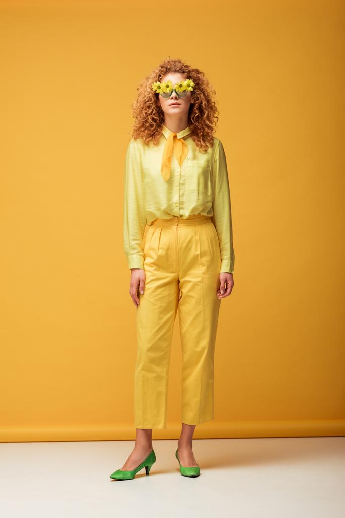 Kıvırcık saçlı, güneş gözlüklü, sarı çiçekli kadın.  - Fotoğraf, Görsel