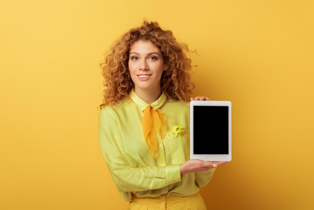felice rossa donna in possesso di tablet digitale con schermo bianco isolato su giallo
  - Foto, immagini