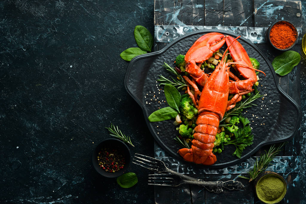 Boiled lobster with vegetables on a black stone plate. Seafood. Top view. Free space for your text. - Photo, Image