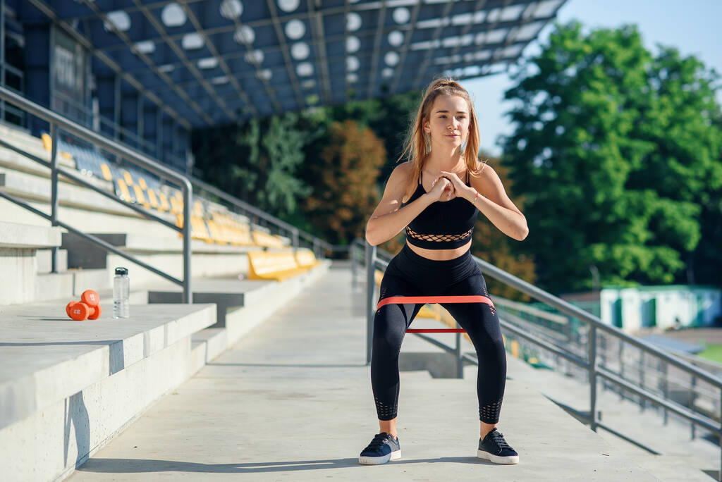 Joven mujer deportiva haciendo ejercicios con banda elástica al aire libre - Foto, imagen
