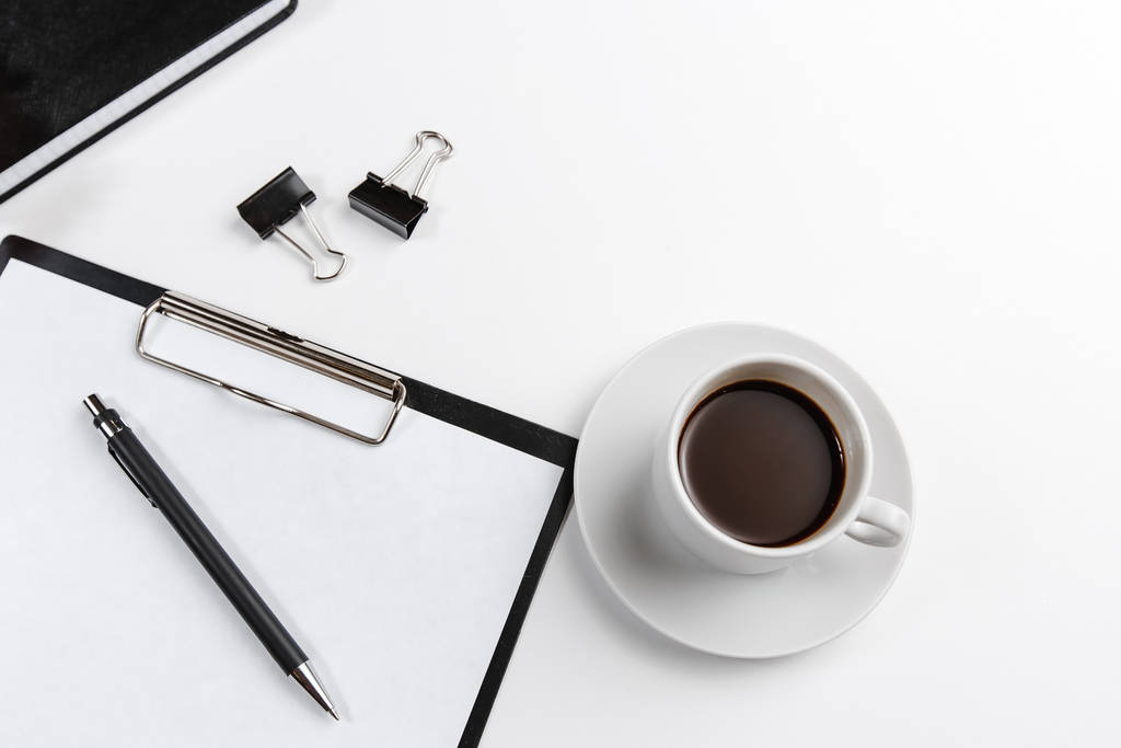 tablet de oficina negra con bolígrafo con taza de café con vista superior de flores sobre fondo blanco. Espacio para texto
 - Foto, Imagen