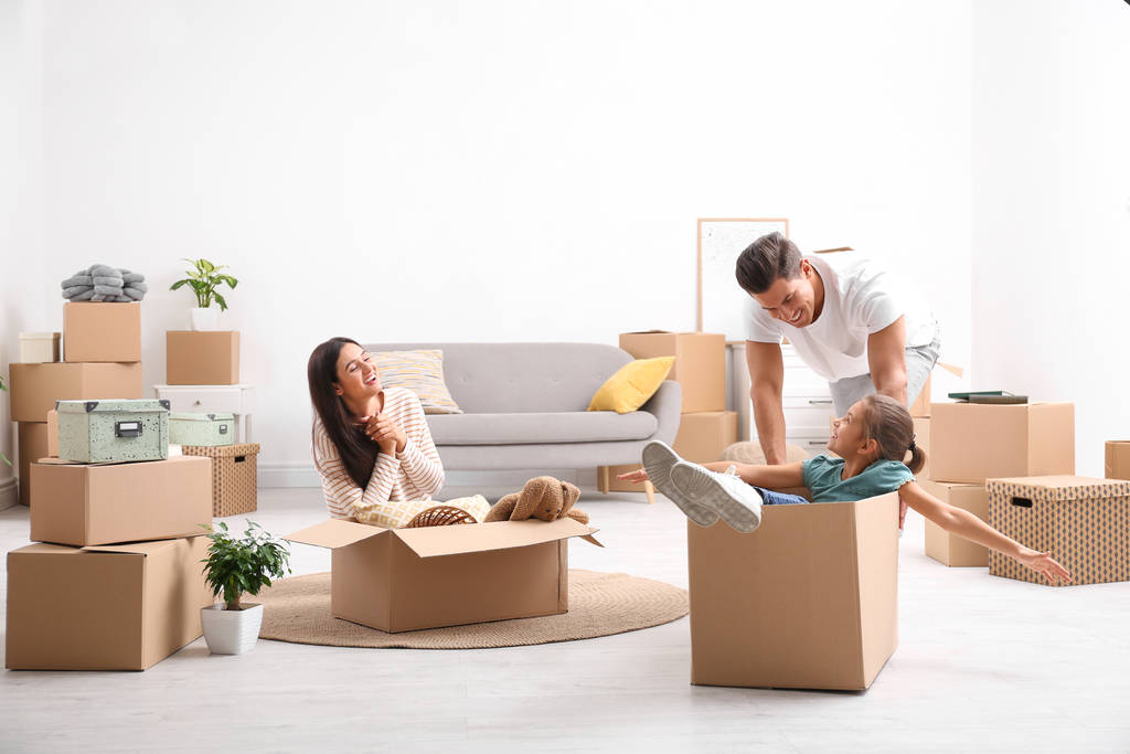 Щаслива сім'я розважається, розпаковуючи рухомі коробки в своєму новому будинку
 - Фото, зображення