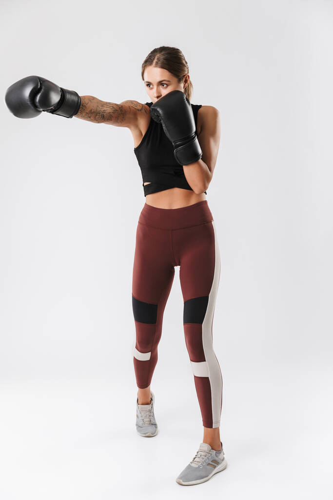 Kuva energinen nainen yllään urheiluvaatteet koulutus nyrkkeily käsineet eristetty valkoisella pohjalla
 - Valokuva, kuva