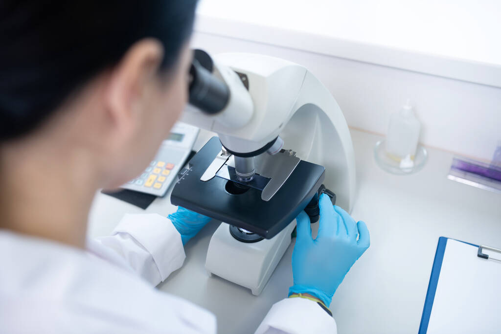 Trabalhador do laboratório bioquímico olhando para o tubo óptico do microscópio
 - Foto, Imagem