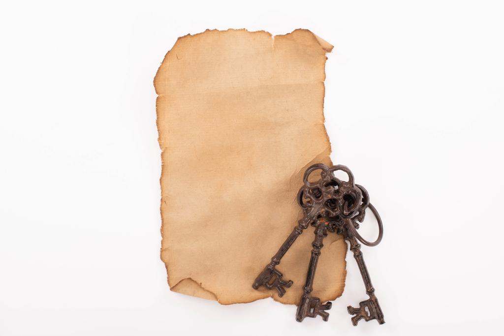 Ansicht von Vintage-Schlüsseln auf gealtertem, leerem Papier isoliert auf Weiß - Foto, Bild