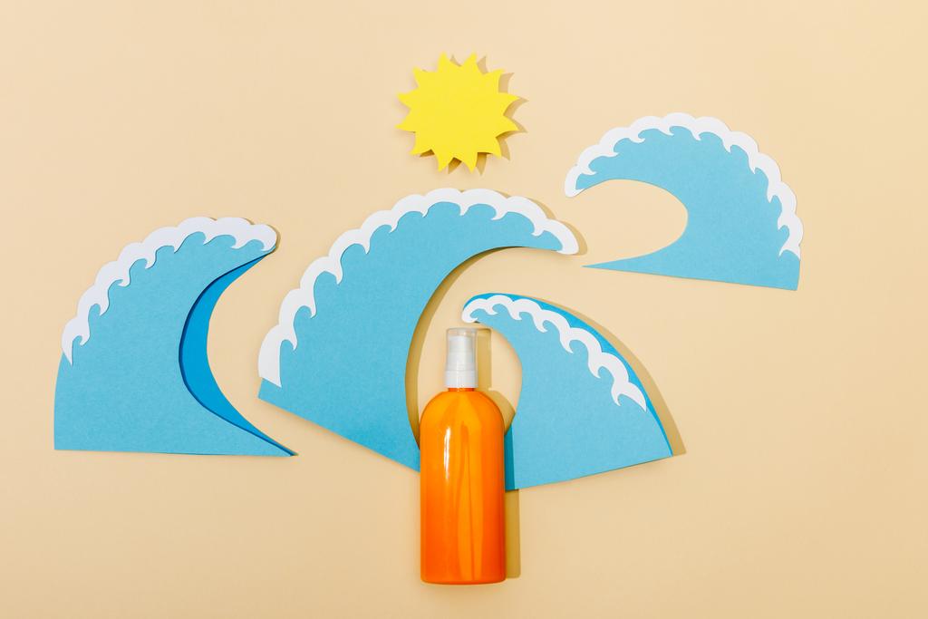 Вид зверху на паперовий вирізаний сонце і морські хвилі з пляшкою сонцезахисного крему на бежевому фоні
 - Фото, зображення