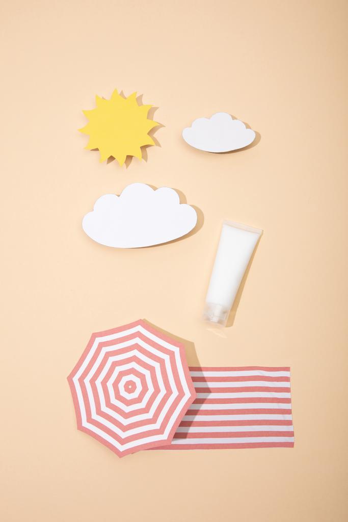 Top kilátás papír vágott nap, felhők, strand esernyő és takaró tubus fényvédő bézs - Fotó, kép