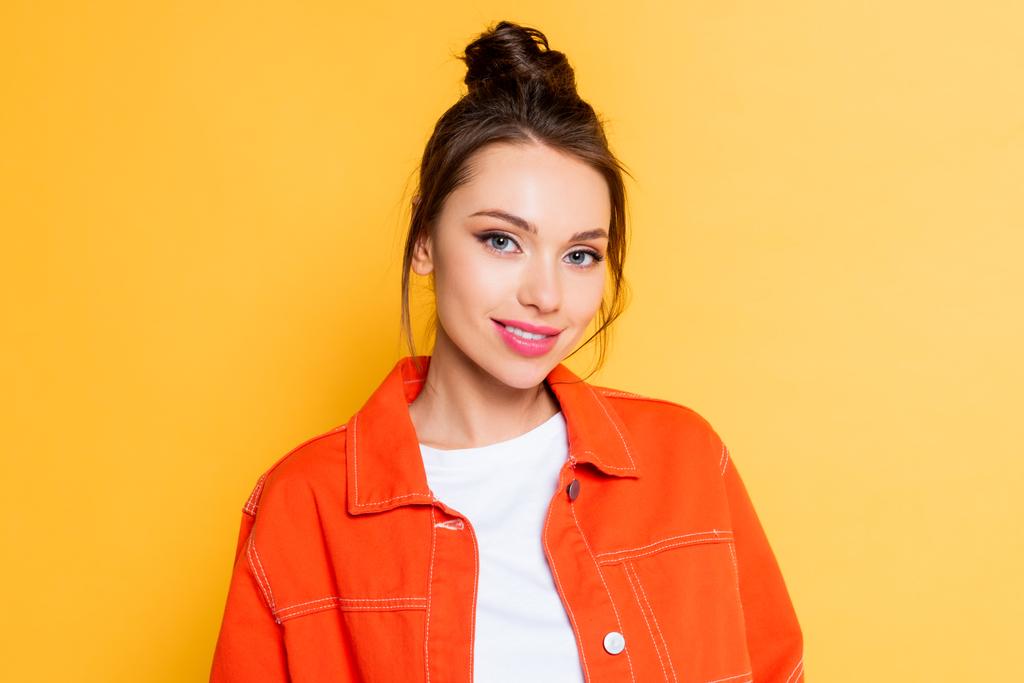 beautiful, confident girl in orange jacket looking at camera isolated on yellow - Photo, Image