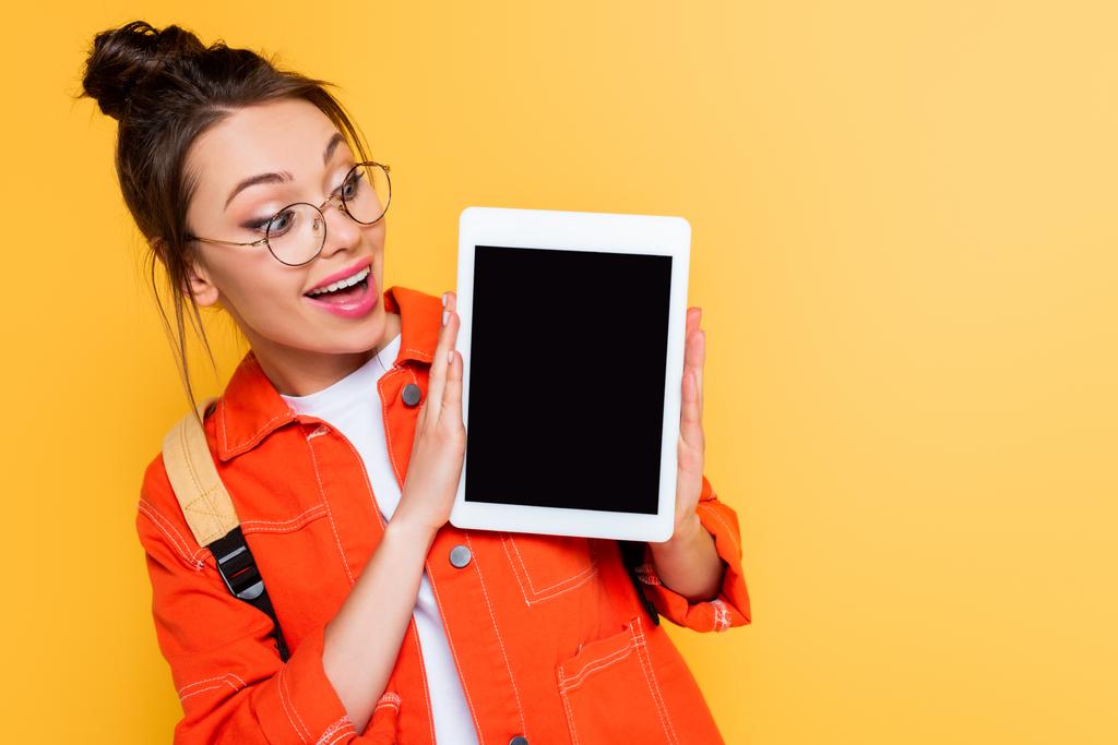 étudiant surpris dans les lunettes montrant tablette numérique avec écran blanc isolé sur jaune
 - Photo, image