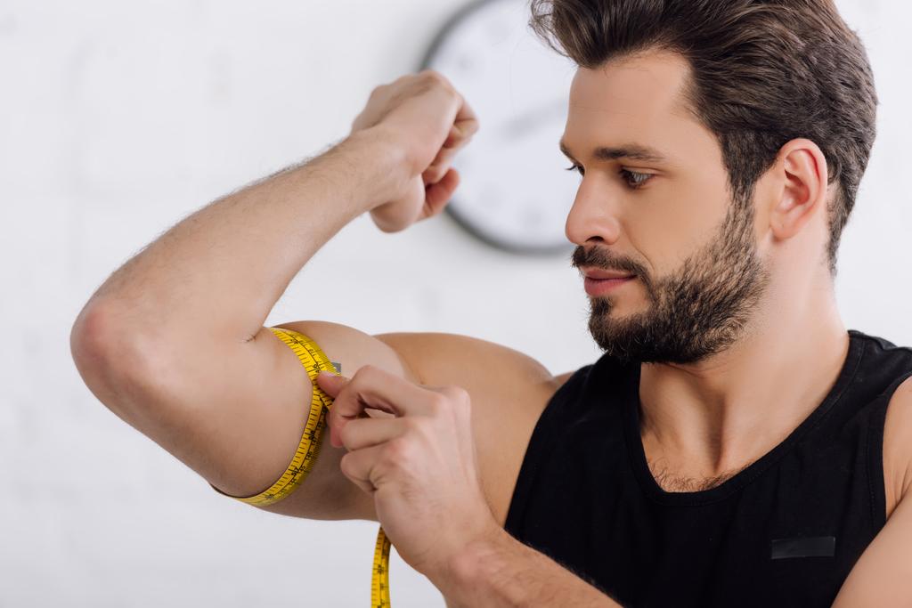 handsome and sportive man measuring muscle on hand   - Photo, Image