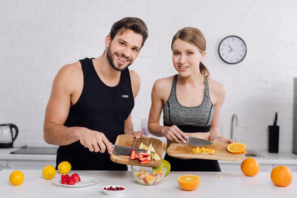 happy man and cheerful woman cooking fruit salad  - Photo, Image