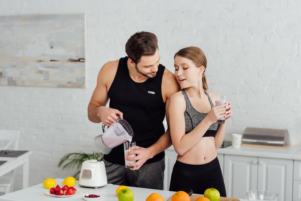 athletic man pouring smoothie in glass near attractive woman  - Photo, Image