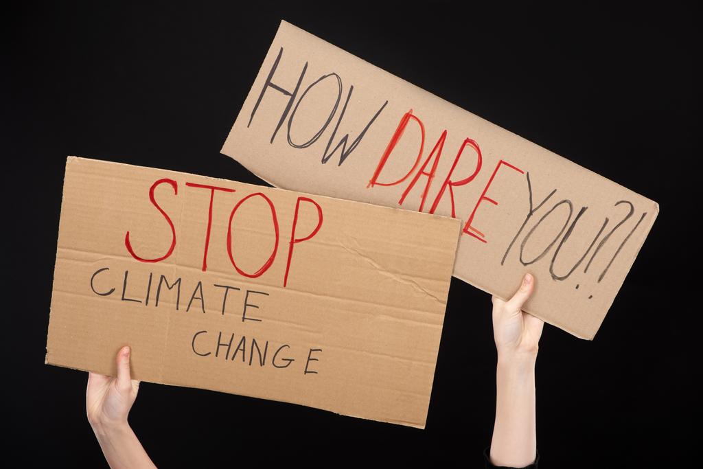Oříznutý pohled na ženu držící plakáty s tím, jak se opovažujete zastavit a zastavit nápisy o změně klimatu izolované na černém konceptu globálního oteplování - Fotografie, Obrázek