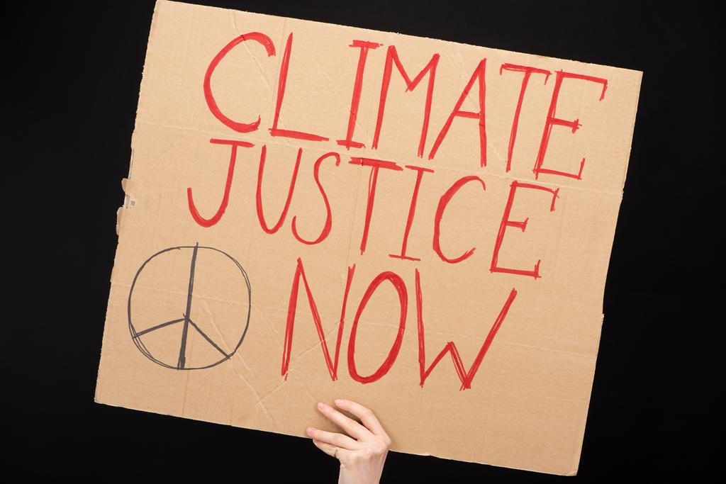Vue partielle de la femme tenant une pancarte avec la justice climatique maintenant lettrée isolée sur le concept noir du réchauffement climatique
 - Photo, image