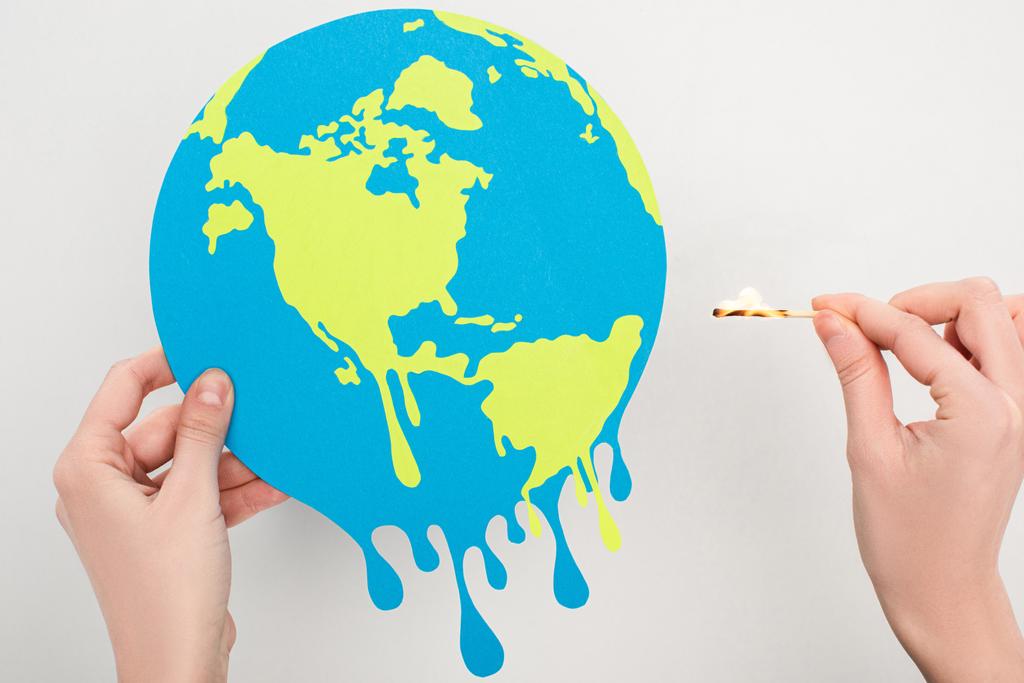 Cropped view of woman holding paper globe and match with fire on white, global warming concept - Photo, Image