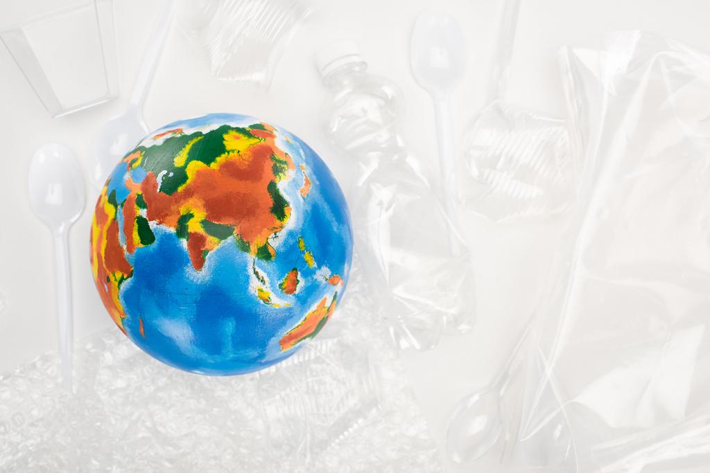 Vista superior del globo sobre basura plástica sobre fondo blanco, concepto de calentamiento global
 - Foto, imagen