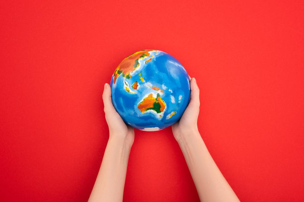 Vue recadrée de la femme tenant le globe sur fond rouge, concept de réchauffement climatique
 - Photo, image