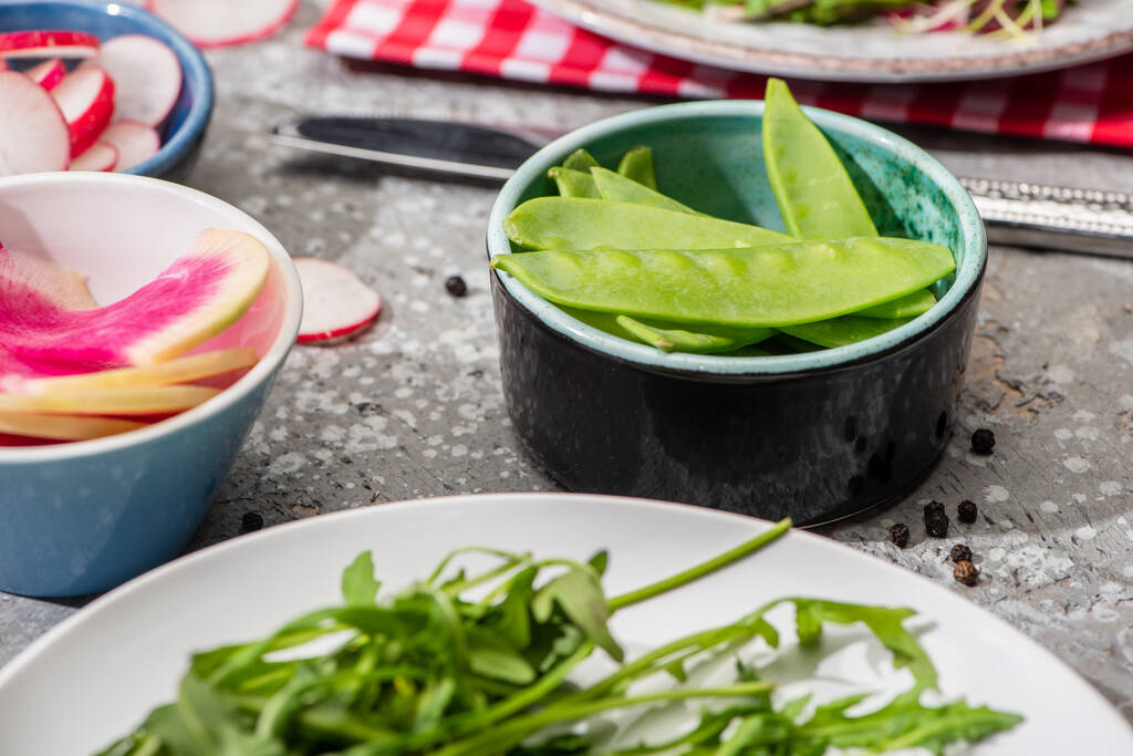 concentration sélective des ingrédients de la salade de radis frais dans les bols sur la surface en béton gris
 - Photo, image