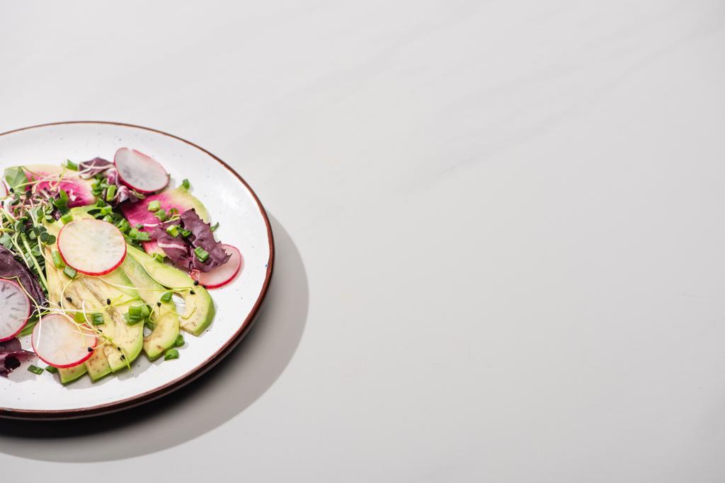 čerstvý ředkvičkový salát se zelení a avokádem na šedém povrchu - Fotografie, Obrázek