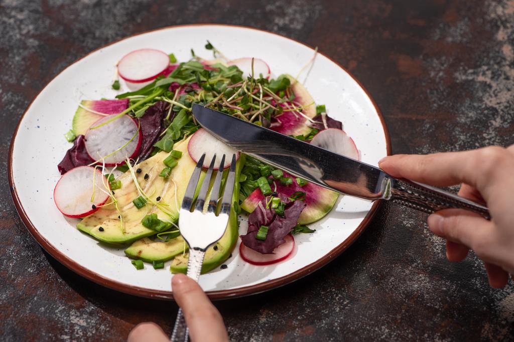 rajattu näkymä nainen syö tuoretta retiisi salaattia vihreät ja avokado ruokailuvälineet
 - Valokuva, kuva