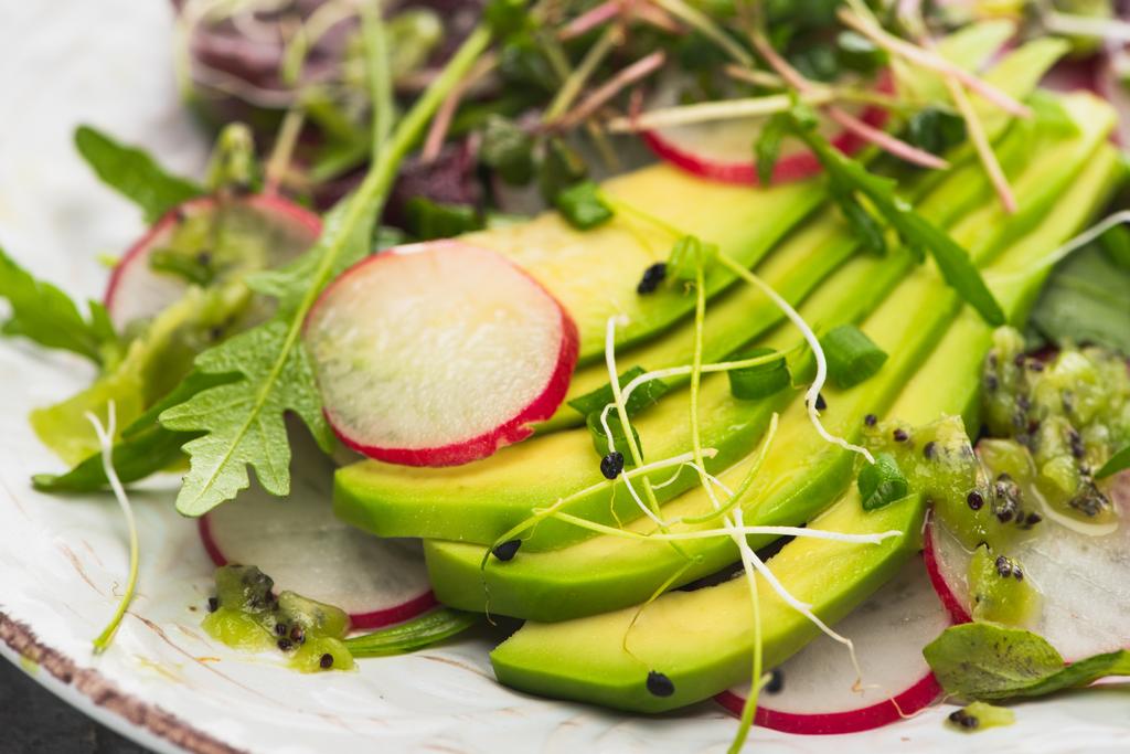 закрыть вид на свежий салат из редьки с зеленью и авокадо
 - Фото, изображение