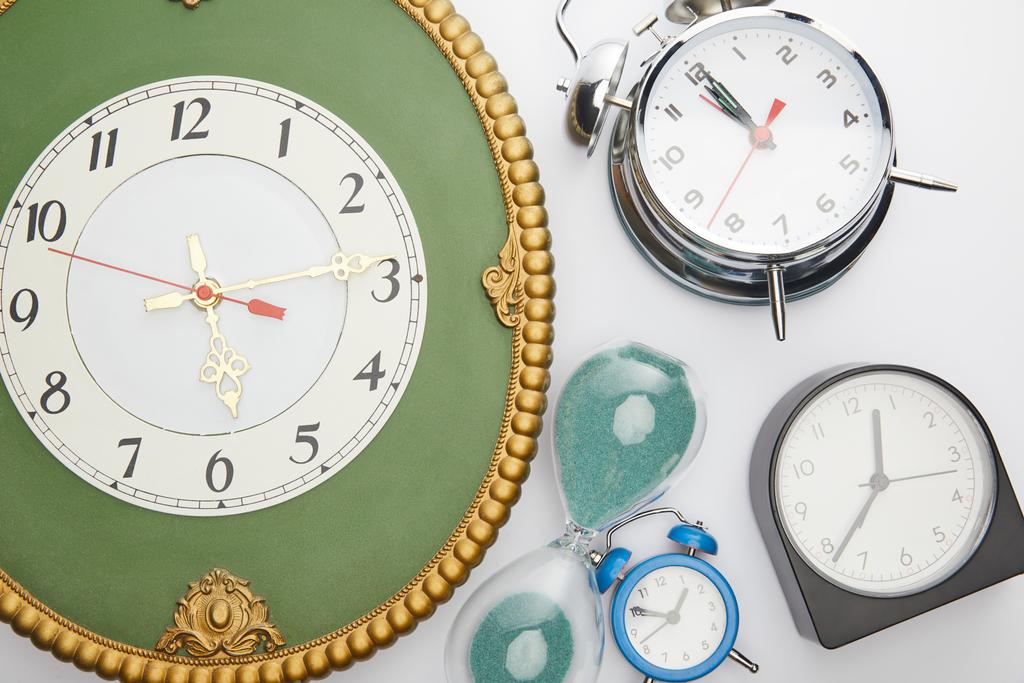 vista superior de los relojes de alarma clásicos y reloj de arena sobre fondo blanco
 - Foto, Imagen