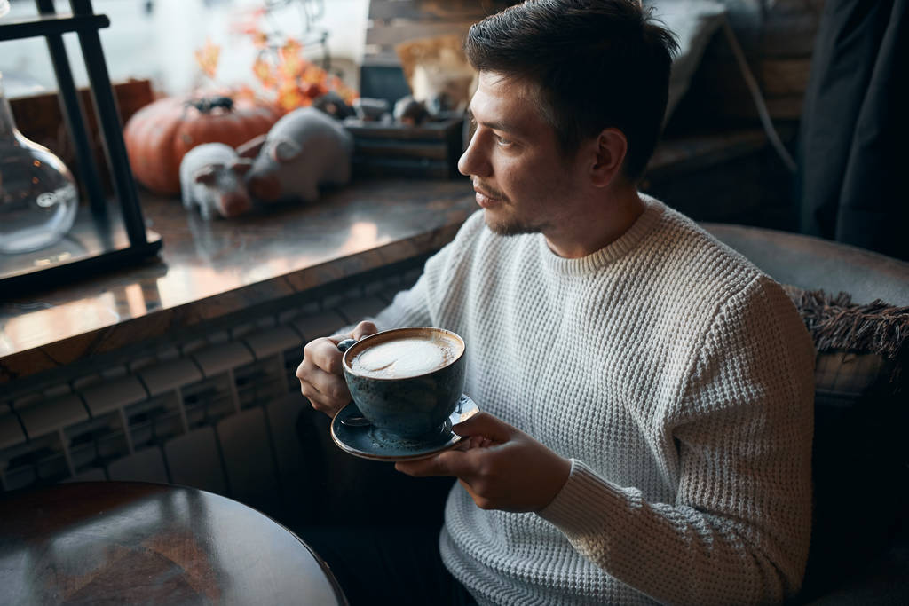 jovem cara agradável tendo coffee break após o trabalho
 - Foto, Imagem