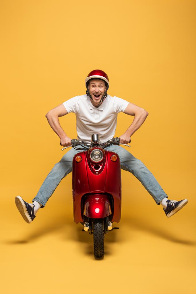 heureux livreur homme en casque scooter équitation sur fond jaune
 - Photo, image