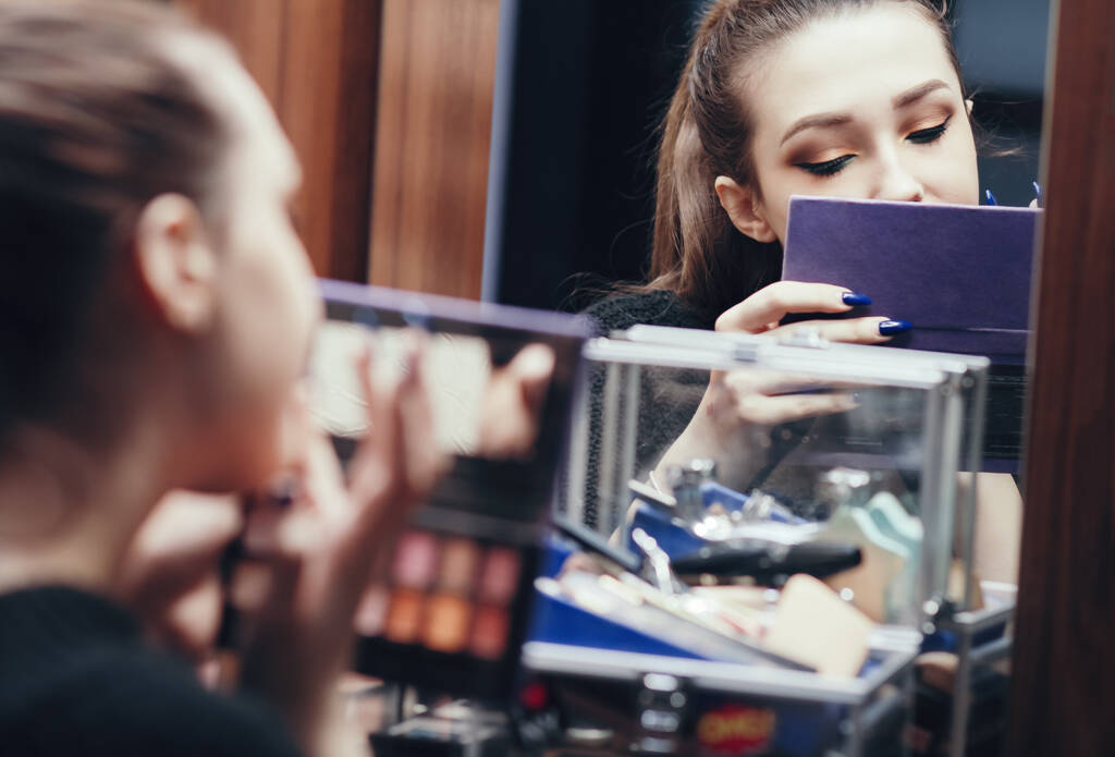 reflexão de uma menina bonita no espelho fazendo maquiagem na mesa de vestir no quarto em casa, jovem preparando rosto, conceito beleza feminina e cosméticos
 - Foto, Imagem