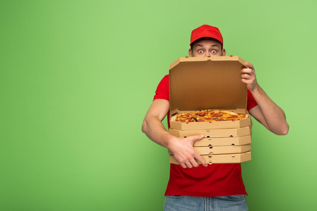 uomo consegna scioccato in uniforme rossa si nasconde dietro scatole di pizza sul verde
 - Foto, immagini