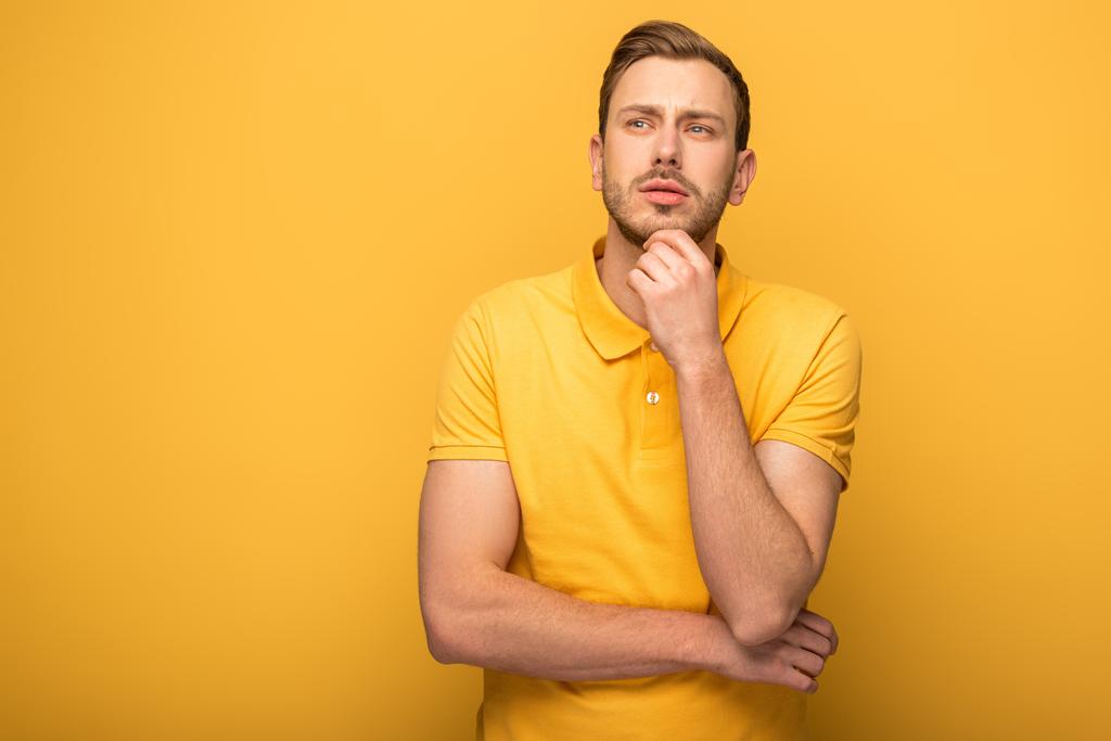 töprengő jóképű férfi sárga ruhában sárga háttér - Fotó, kép