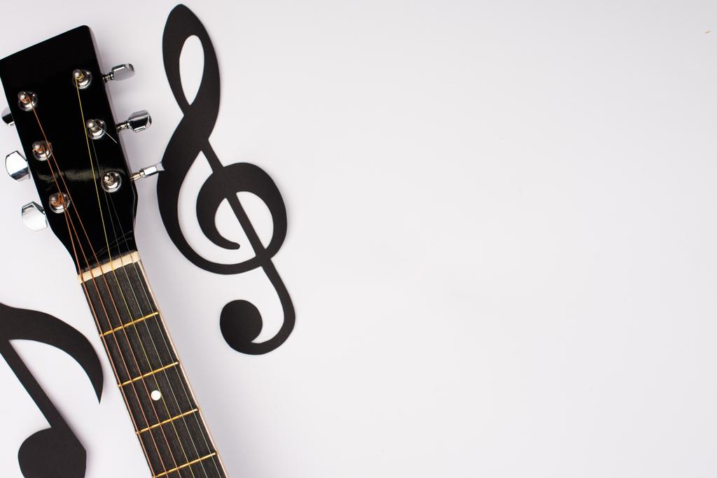 Vista superior de papel cortado notas musicales y guitarra acústica sobre fondo blanco
 - Foto, Imagen