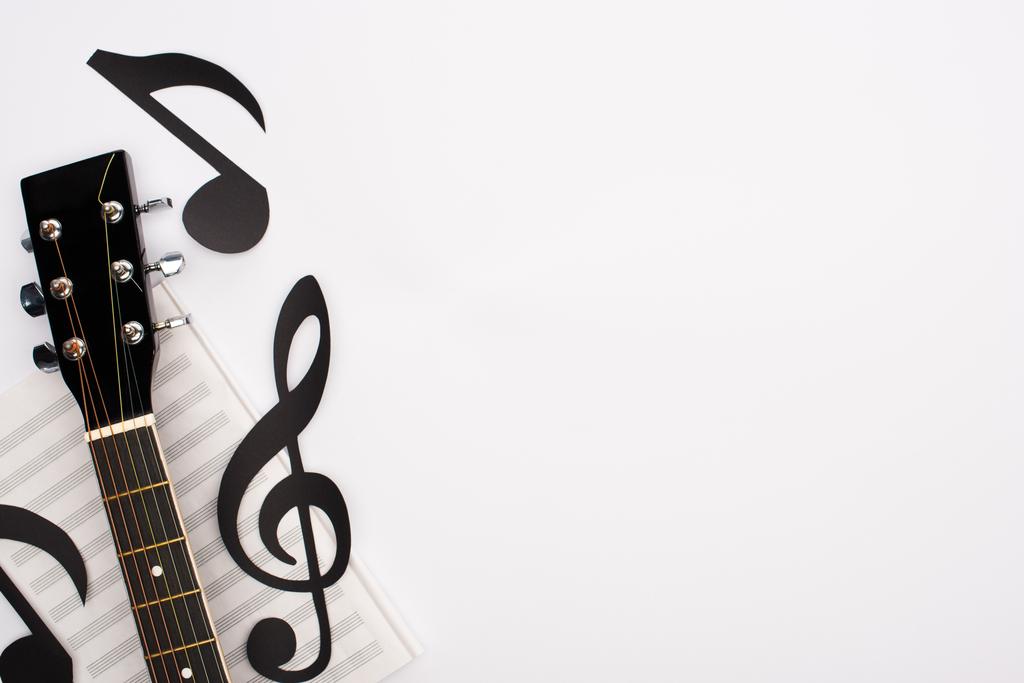Top view of paper cut notes, music book and acoustic guitar on white background - Photo, Image