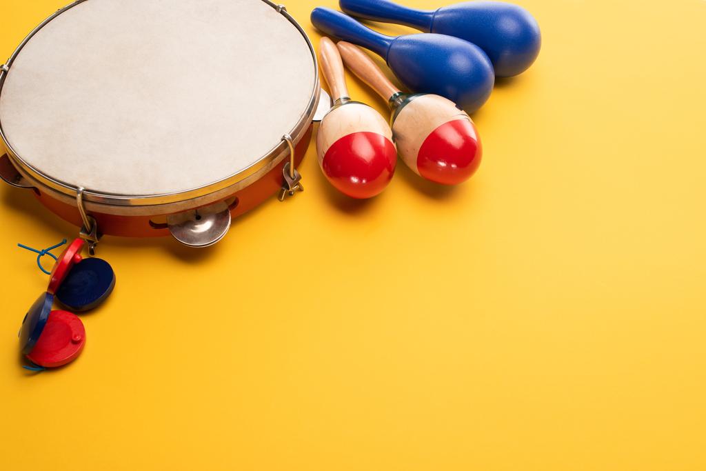 Houten kleurrijke en blauwe maracas met tamboerijn en castagnetten op gele achtergrond - Foto, afbeelding