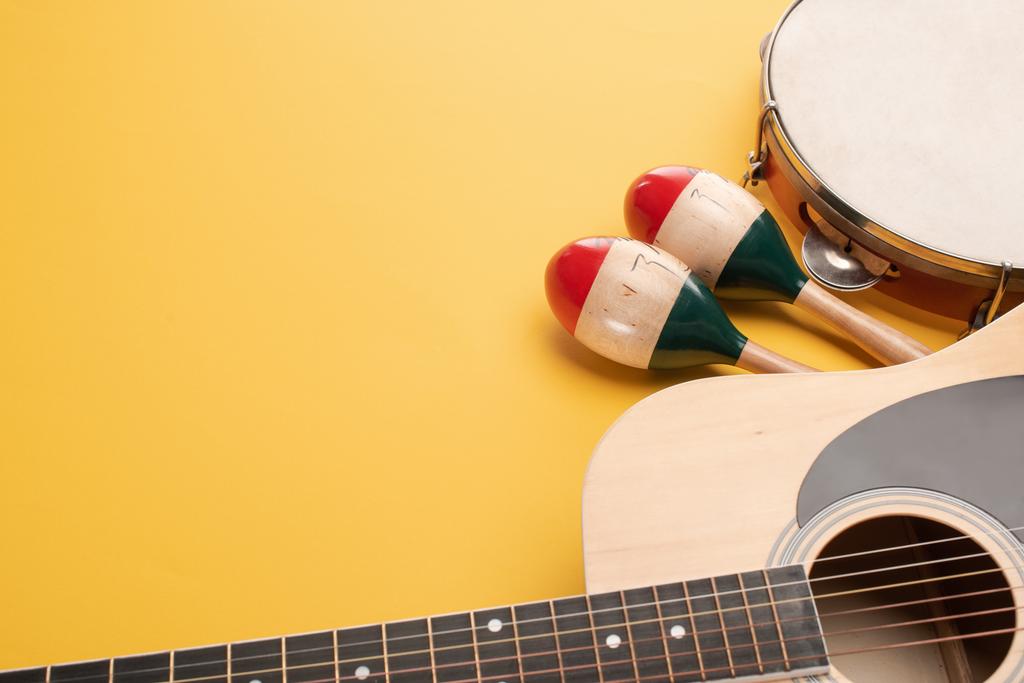 Drewniane kolorowe marakasy z tamburynem i gitarą akustyczną na żółtym tle - Zdjęcie, obraz