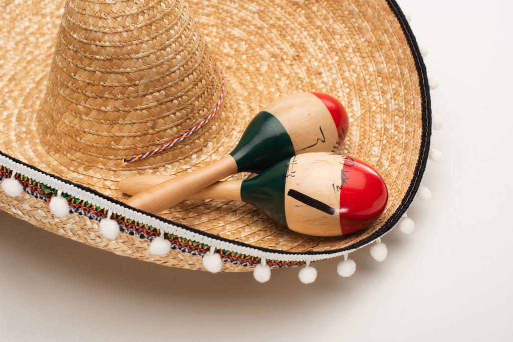 close-up zicht op houten maracas op sombrero op witte achtergrond - Foto, afbeelding