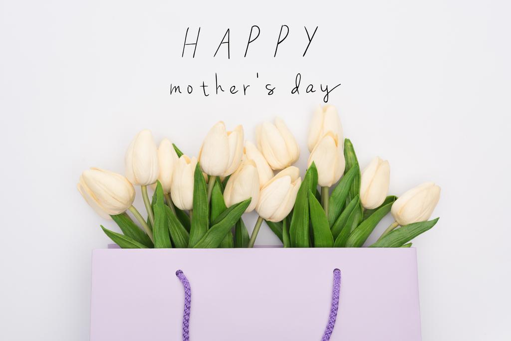 Beyaz, mutlu anneler gününde izole edilmiş mor alışveriş çantasındaki lalelerin üst görüntüsü. - Fotoğraf, Görsel
