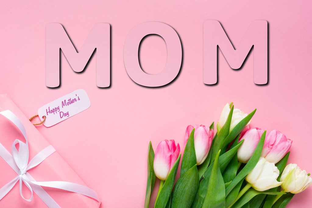 Widok z góry prezent z szczęśliwy dzień matki napisy na papierze etykieta w pobliżu tulipany na różowym tle, Mama ilustracja - Zdjęcie, obraz