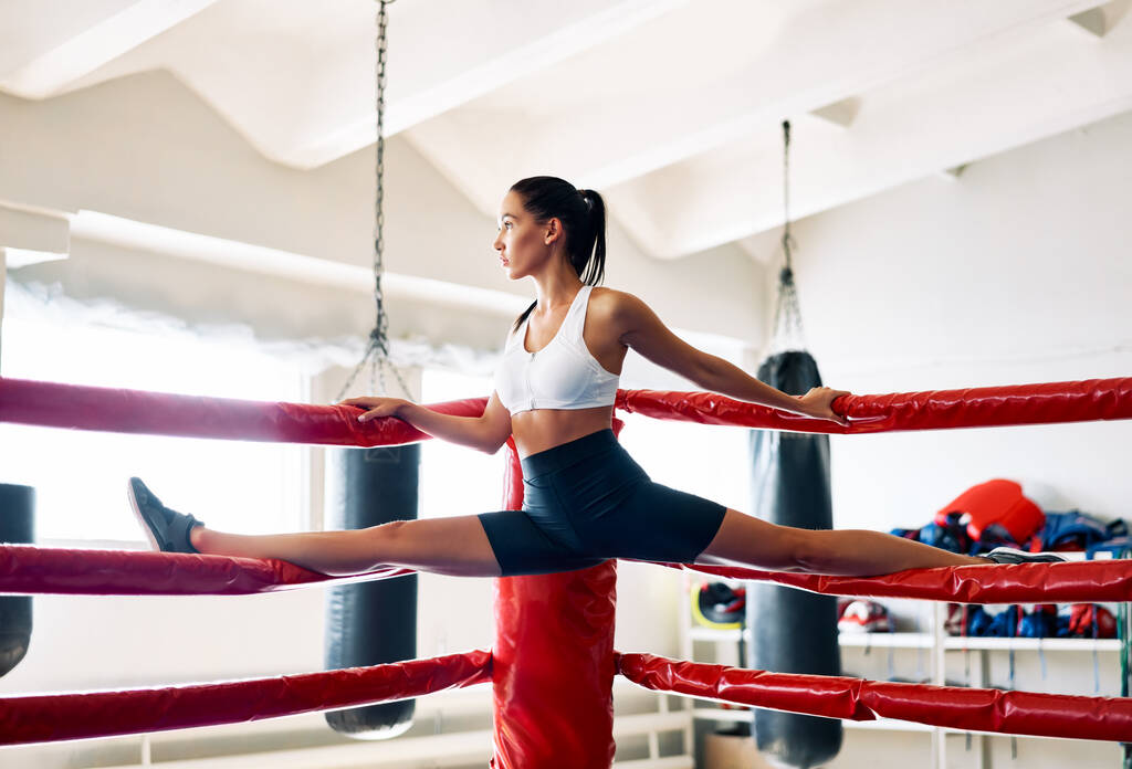Спортивная молодая женщина делает шпагат на верхушке боксерской веревки. Растяжки
 - Фото, изображение