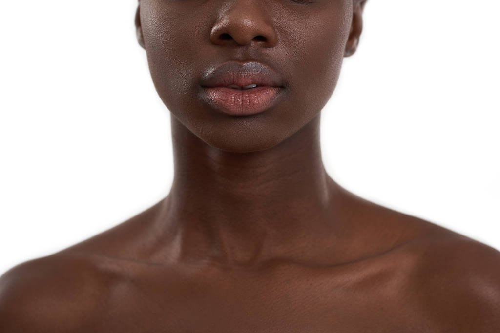 Perfecte gloeiende huid. Gewassen foto van Afrikaanse vrouw met grote natuurlijke lippen staan tegen witte achtergrond - Foto, afbeelding
