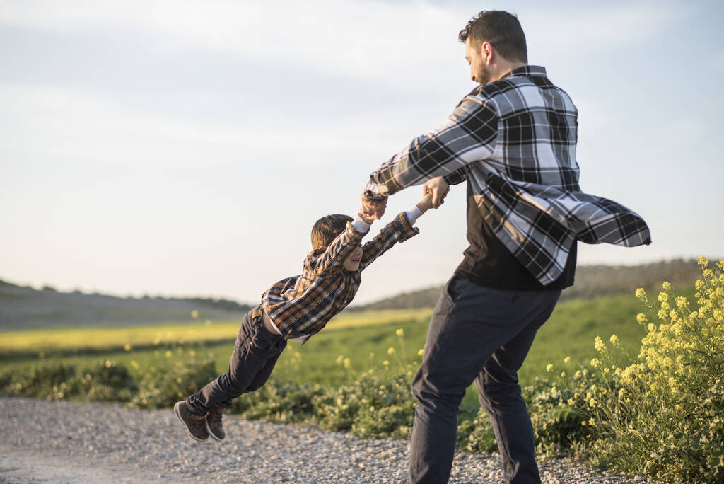 Spinnender Vater packt Sohn mit Armen, dreht sich - Foto, Bild